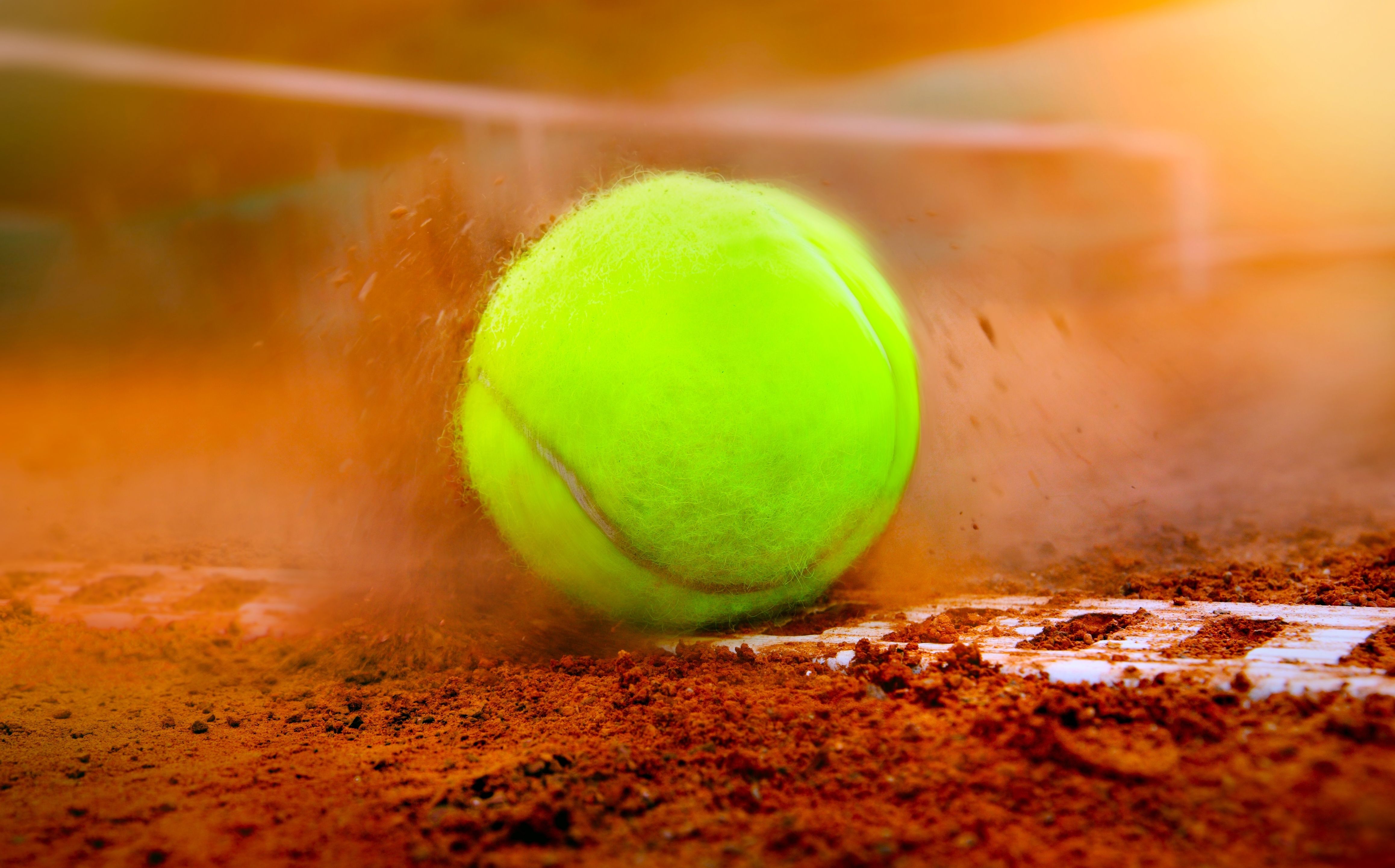 Tennis ball hit the clay court in close up