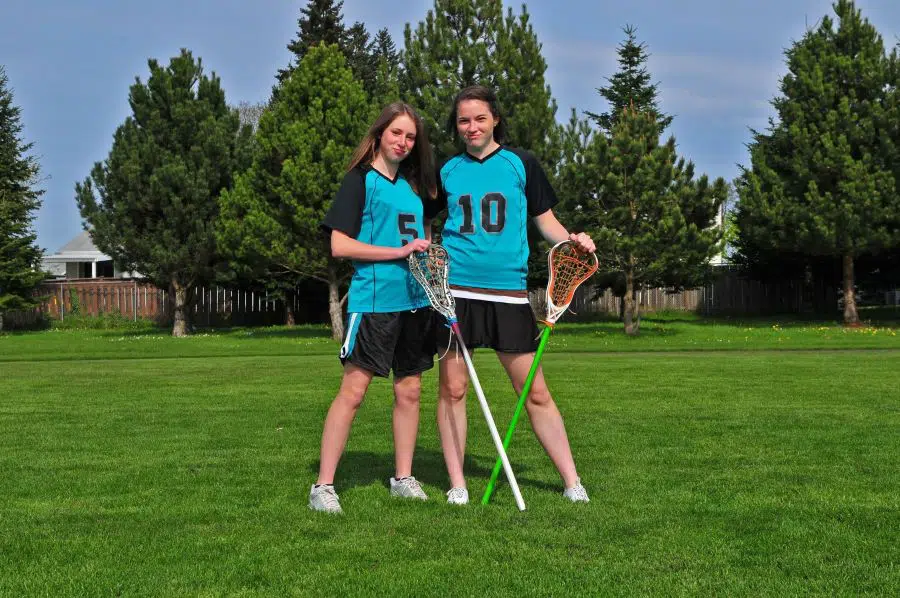 two girls playing lacrosse