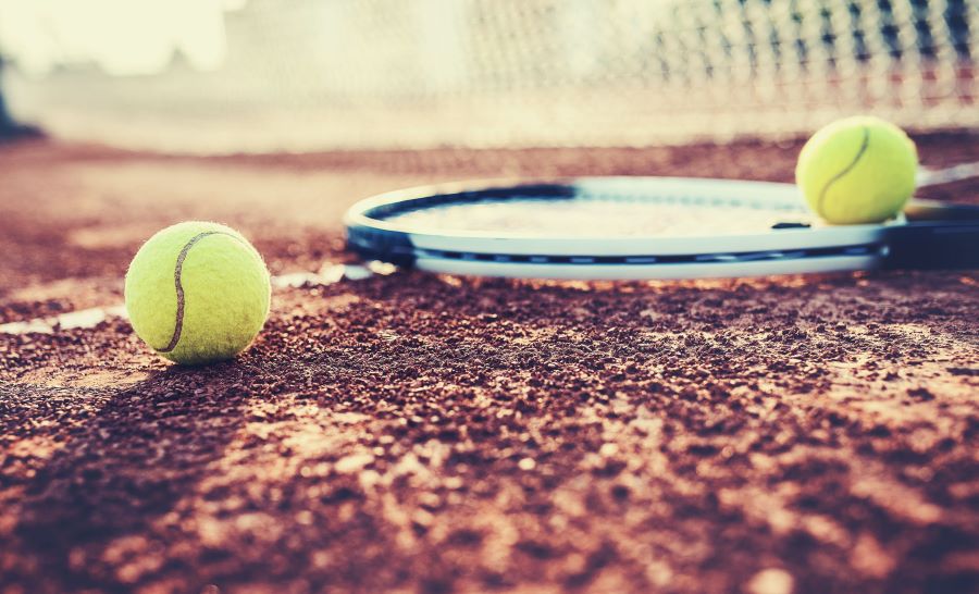 tennis racket on court with two tennis balls
