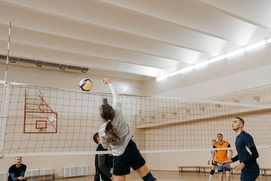 A jumping woman smashing a volleyball over the net