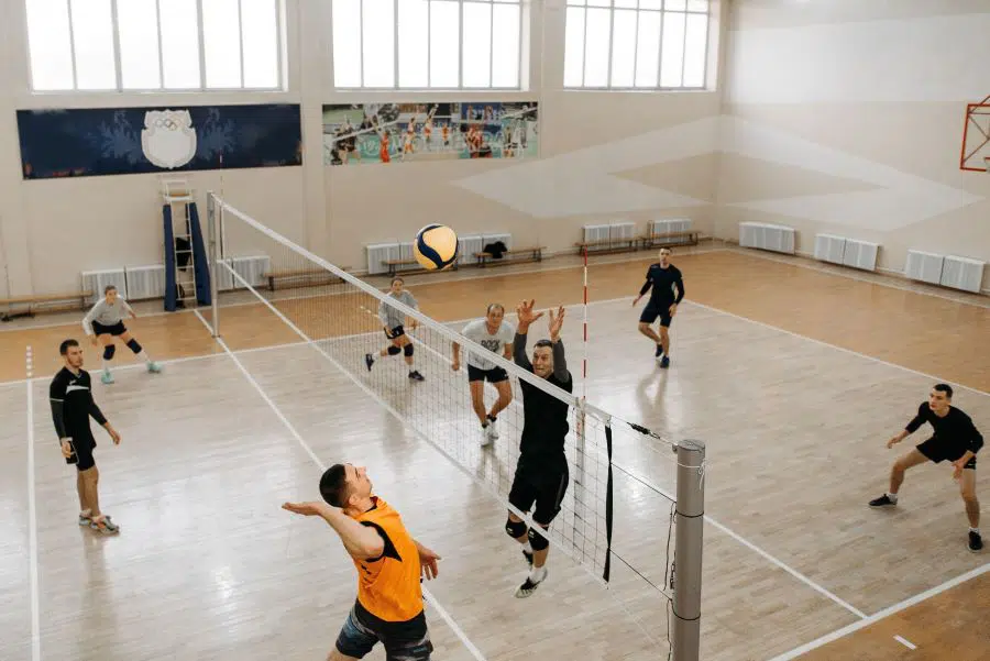 Two teams playing volleyball in a gymnasium