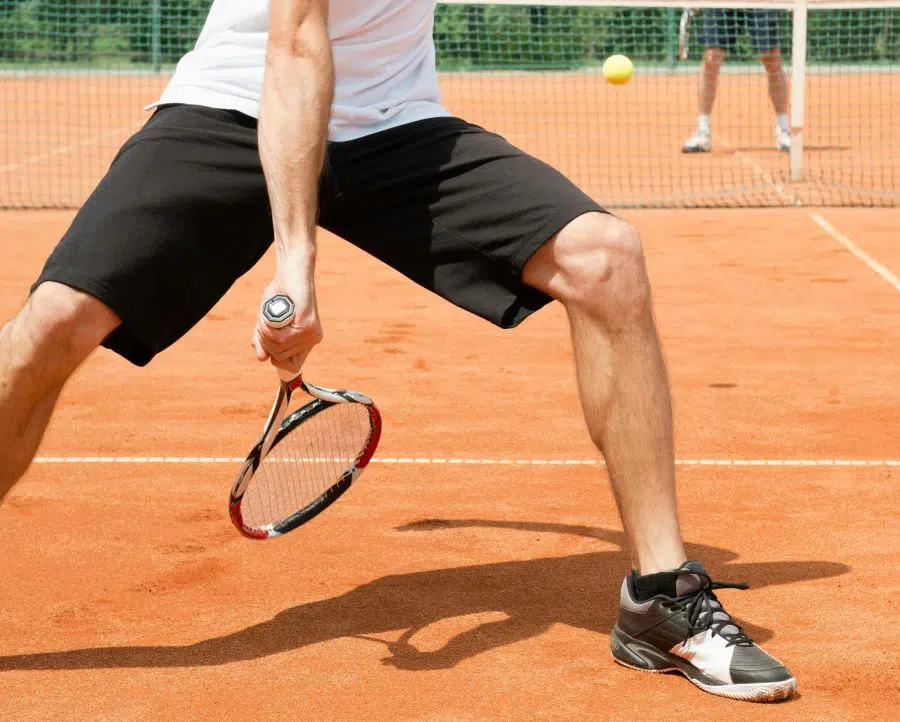 Tennis player trying a trick-shot, hitting a ball between his legs