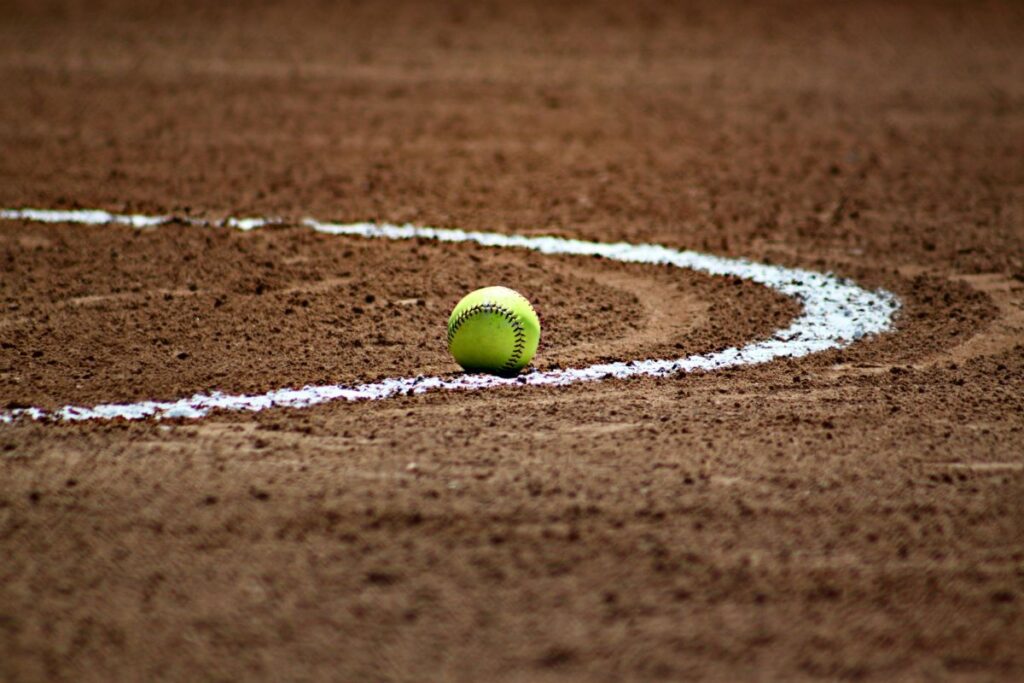 softball lying on a softball pitch, next to a white line painted on the ground