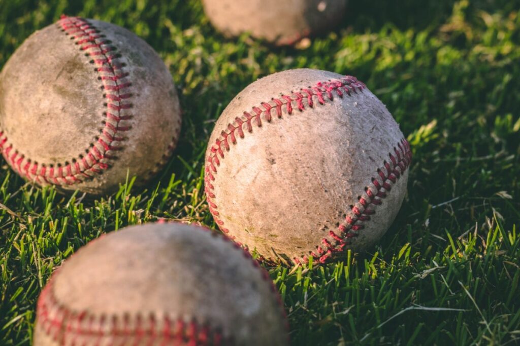 Four baseballs lying in the grass, up close shot