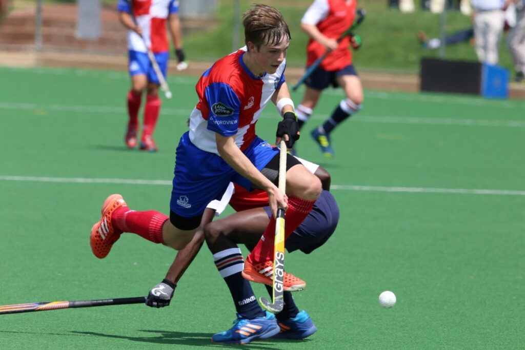 Players playing field hockey on an artificial pitch