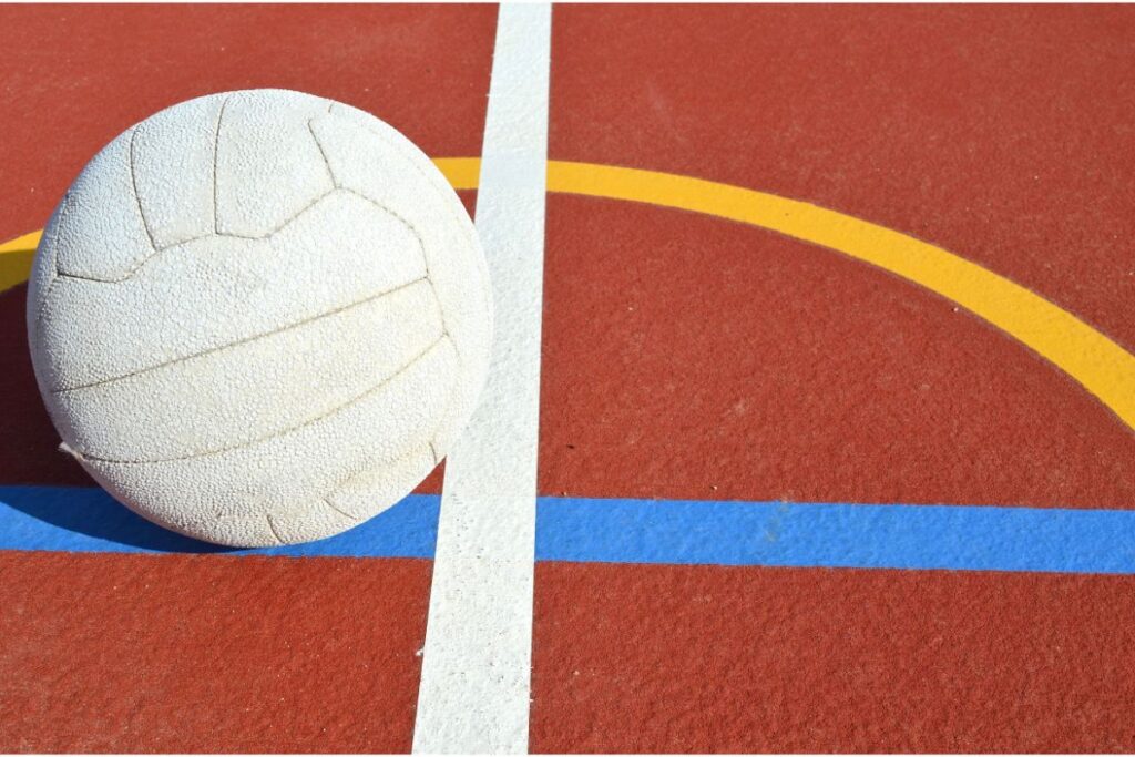 A netball ball lying on a netball court, next to painted court lines